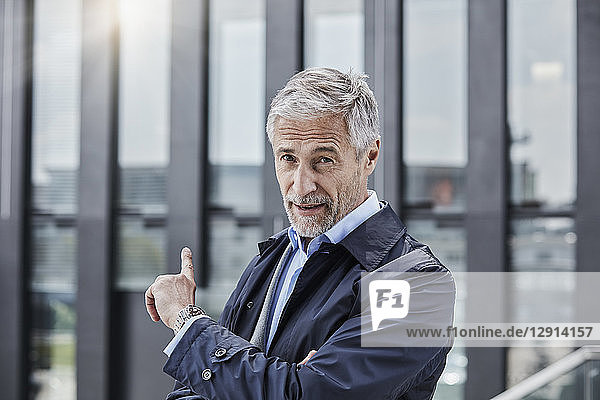 Germany  Duesseldorf  portrait of businessman pointing at office building at Media Harbour