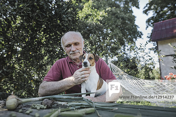 Senior man sitting with dog at garden table