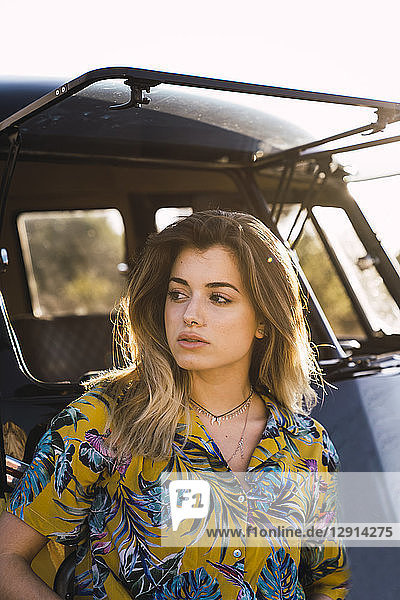 Portrait of young woman outside van looking around