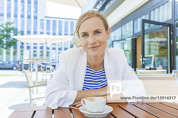 Smiling blond businesswoman at sidewalk cafe