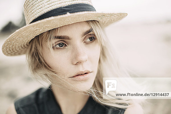 Portrait of daydreaming young woman wearing straw hat in nature