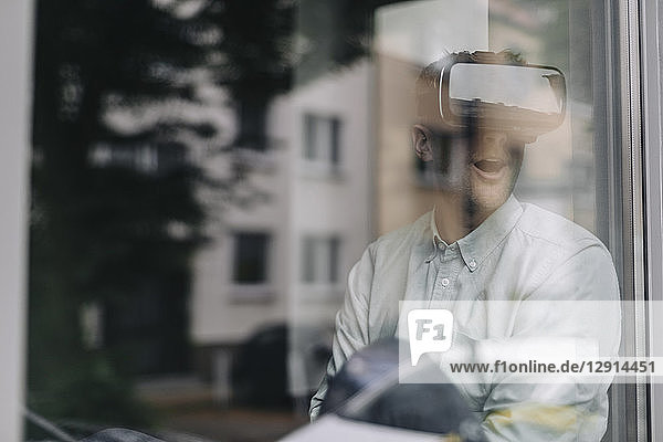Young man sitting at the window  using VR glasses