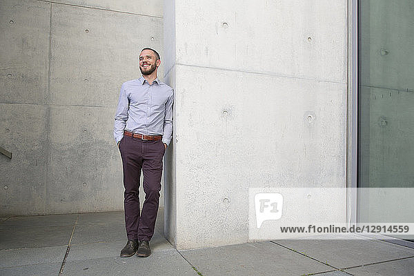 Smiling businessman leaning against a wall