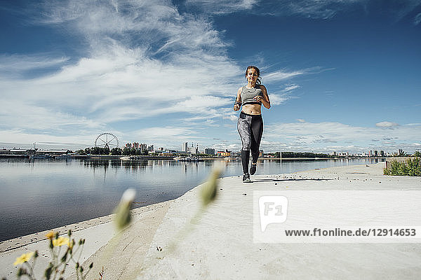 Young athletic woman running at the riverside