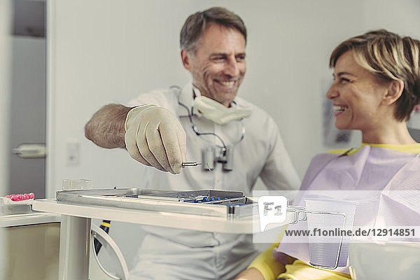 Dentist putting instruments on tray after treatment  looking at his smiling patient