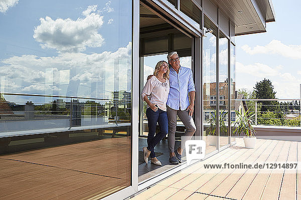 Smiling mature couple standing at roof terrace at home