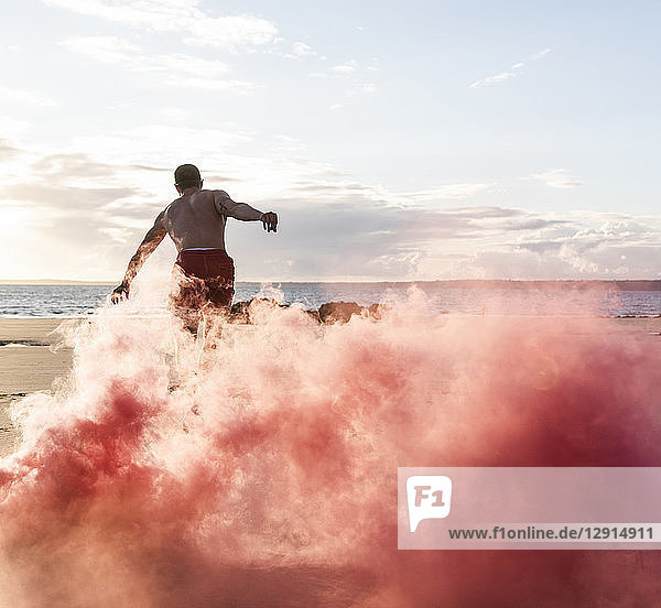 Man doing movement training at the beach with red smoke