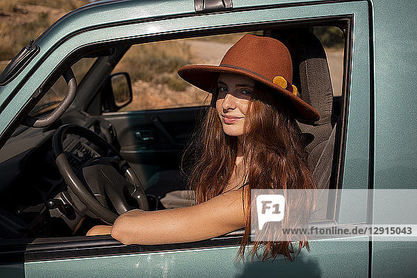 Portrait of smiling young woman wearing a hat sitting in a car