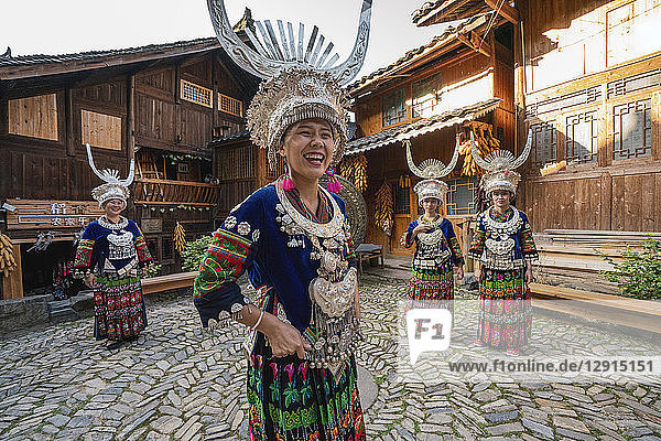 China  Guizhou  happy Miao women wearing traditional dresses and headdresses standing on village square