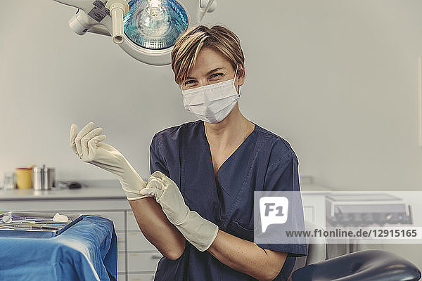 Dental surgeon wearing surgical mask  putting on surgical gloves