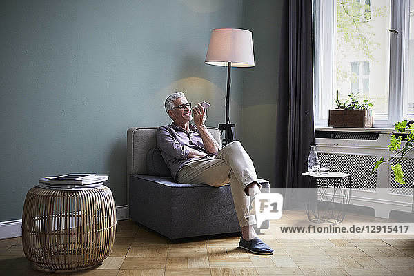 Mature man using cell phone at home