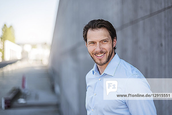 Portrait of smiling businessman at concrete wall