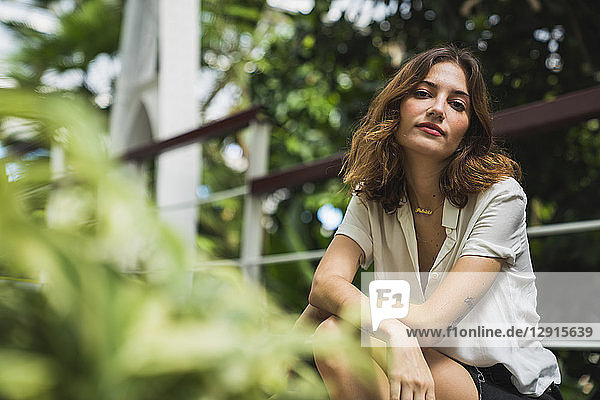 Young woman sitting in greenhouse  portrait