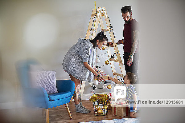 Modern family at home at Christmas time using ladder as Christmas tree