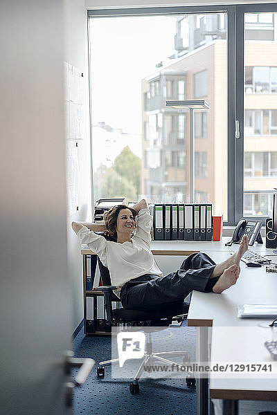 Businesswoman relaxing in office with feet on desk