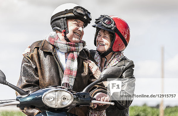 Happy senior couple riding motor scooter