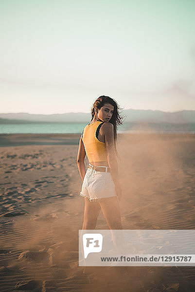 Portrait of teenage girl standing on the beach at sunset