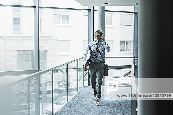 Happy businessman carrying surfboard in office