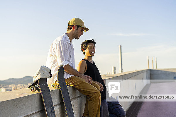 Two young men resting next to skateboards at a wall