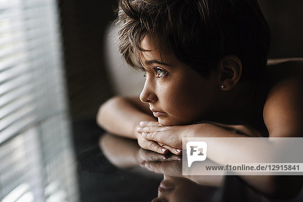 Portrait of little girl looking out of window