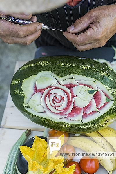 Close-up of man decorating a watermelon with carving tool
