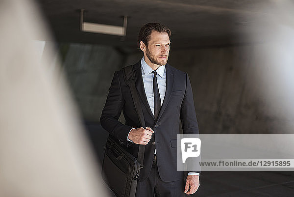 Confident businessman with laptop bag standing in underpass