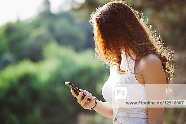 Redheaded woman using cell phone outdoors