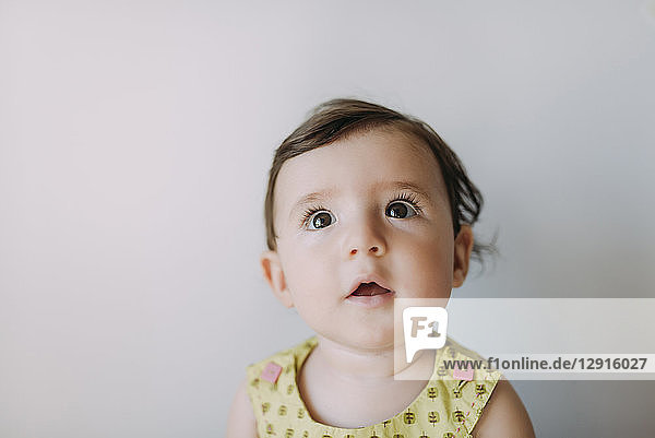 Surprised baby girl looking up on white background
