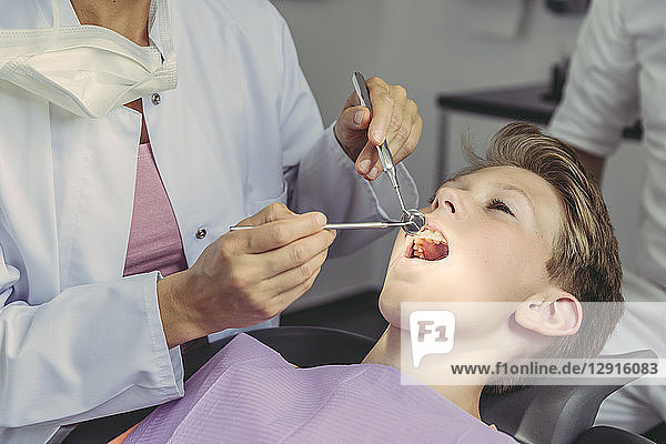 Dentist examining boy's teeth with dental instruments