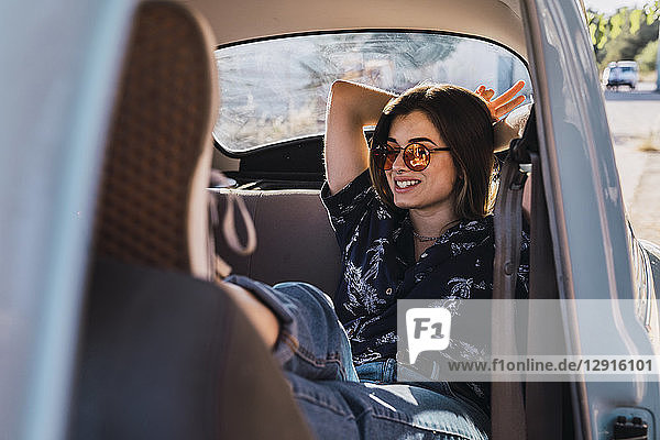 Smiling young woman wearing sunglasses sitting in a car