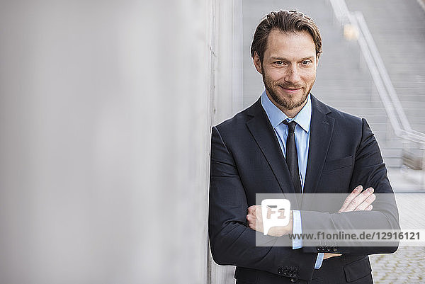 Portrait of confident businessman at concrete wall