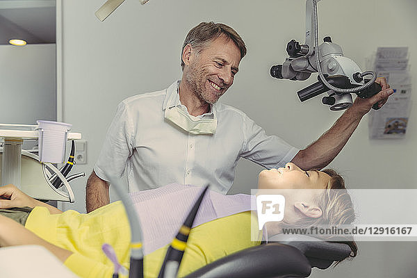 Dentist examining his patient  using dental microscope