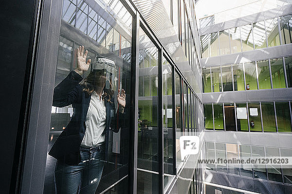 Businesswoman wearing VR goggles  standing at window