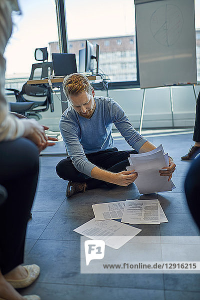 Businessman organising papers on the floor in office