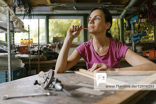Mature woman at workbench in her workshop thinking
