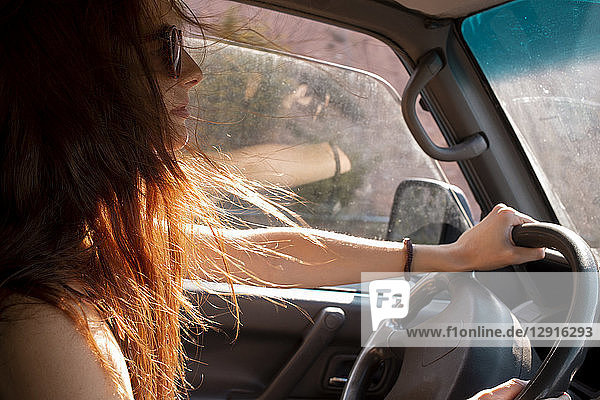 Young woman with windswept hair driving a car