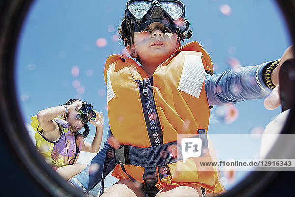 Toddler wearing life jacket and diving goggles with brother in background