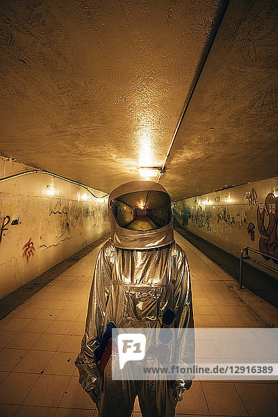 Spaceman in the city at night standing in underpass