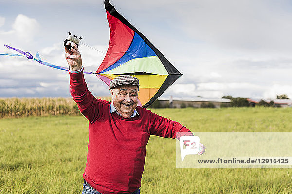 Happy senior man flying kite in rural landscape
