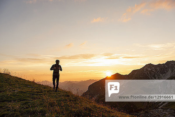 Germany  Bavaria  Oberstdorf  man on a hike in the mountains at sunset