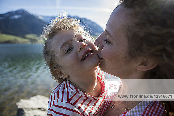 Austria  Tyrol  Walchsee  mother kissing happy daughter at the lake