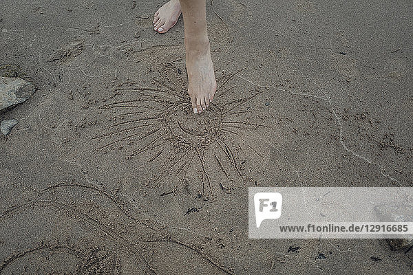 Bare foot drawing son in sand