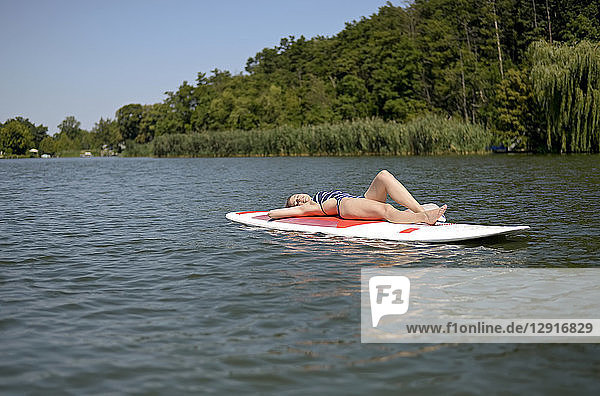 Germany  Brandenburg  woman relaxing on paddleboard on Zeuthener See