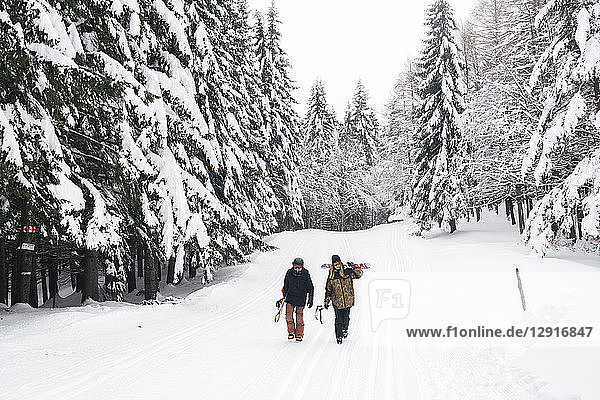 Italy  Modena  Cimone  couple with skiers and snowboard walking in winter forest