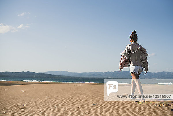 Back view of teenage girl walking on the beach