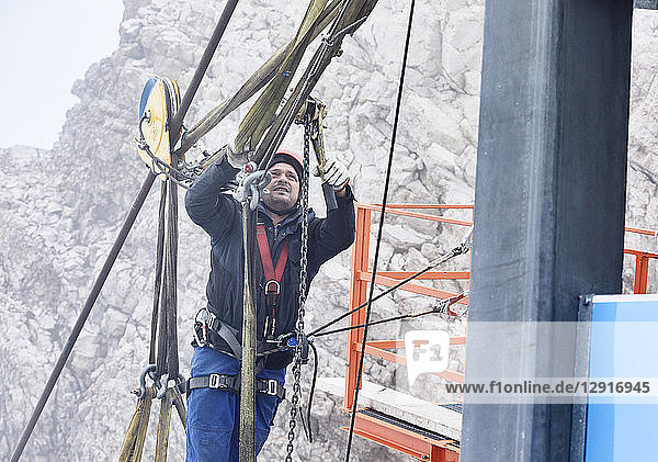 Germany  Bavaria  Garmisch-Partenkirchen  Zugspitze  installer working with rope pulley on goods cable lift