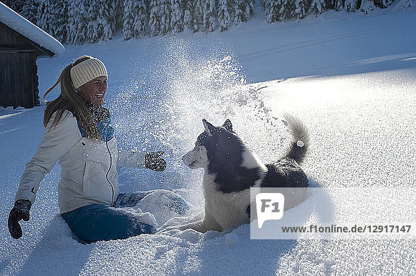 Austria  Altenmarkt-Zauchensee  happy young woman playing with dog in snow