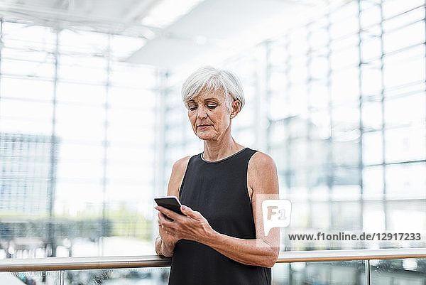 Senior woman standing at railing using cell phone