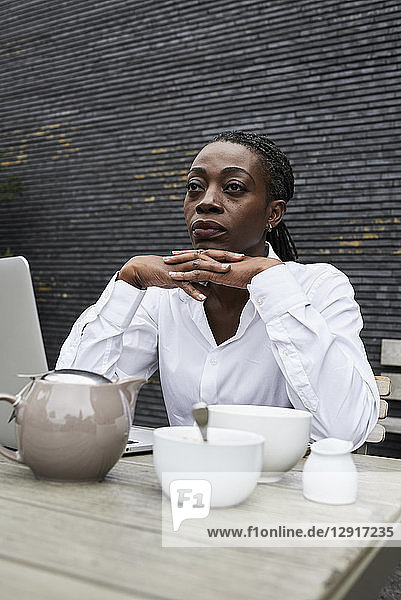 Portrait of pensive businesswoman sitting on terrace of a coffee shop