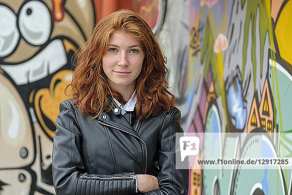 Italy  Finale Ligure  portrait of redheaded teenage girl wearing black leather jacket in front of mural